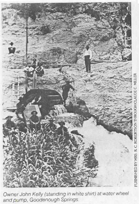 Historic black and white photograph of men at a water wheel and pump beside the flowing Goodenough Springs, before the reservoir.